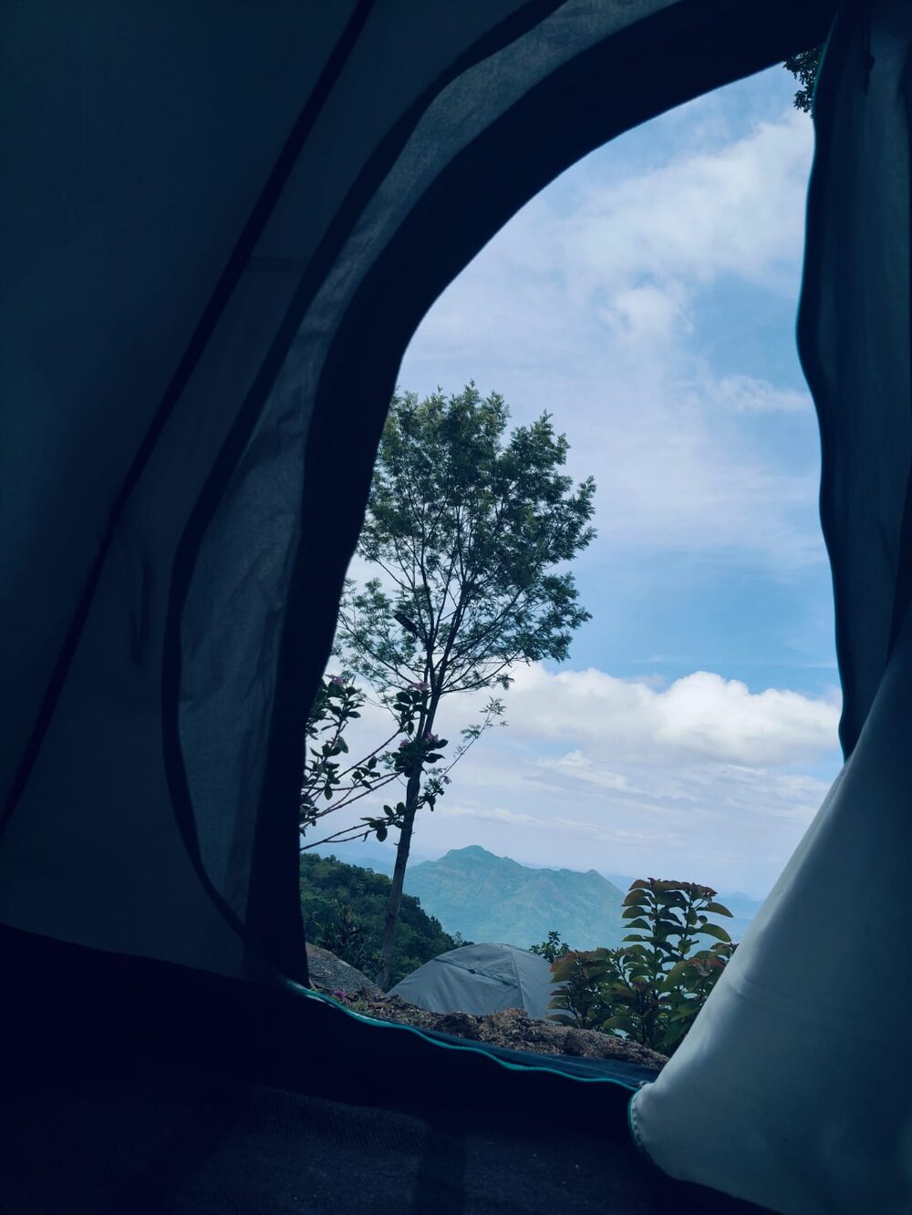 The view of mist-wrapped mountains framed by an open tent door at dawn